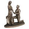 Bronze statue of a man on one knee proposing to a woman on a white background