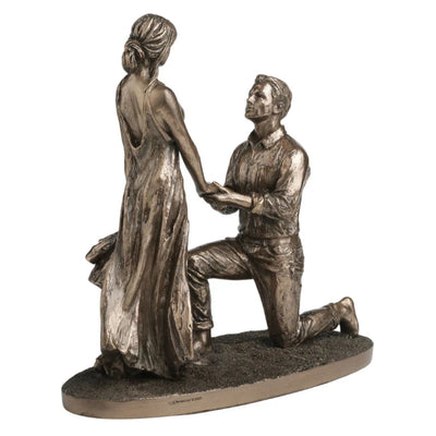 Bronze statue of a man on one knee proposing to a woman on a white background